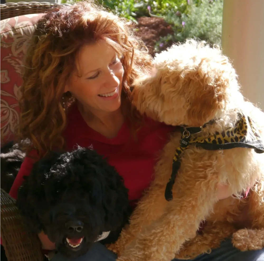 Mary sitting outside with two Valley Vineyard Labradoodles
