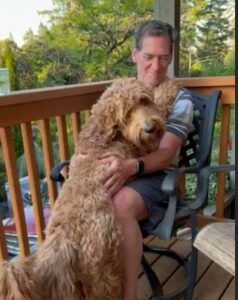 Bisbee standing up to hug a man on the deck